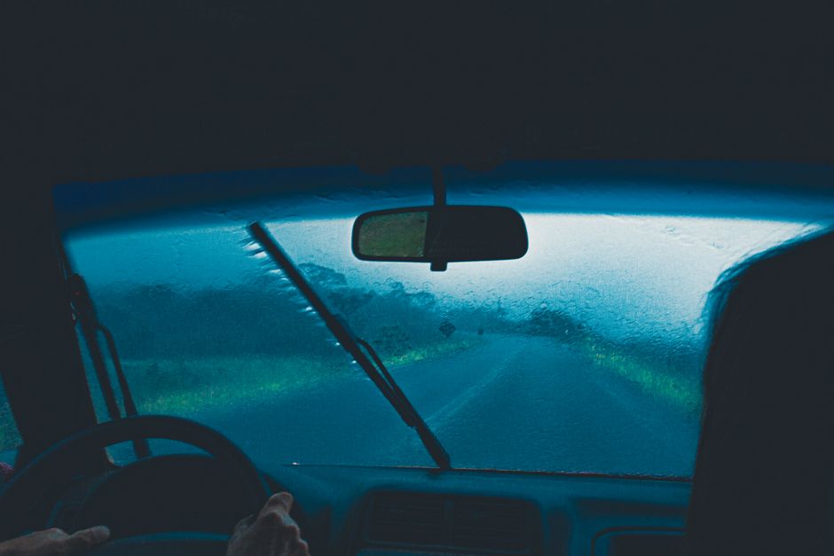Heavy monsoon rain on a Malaysian highway with car headlights and wet road at dusk