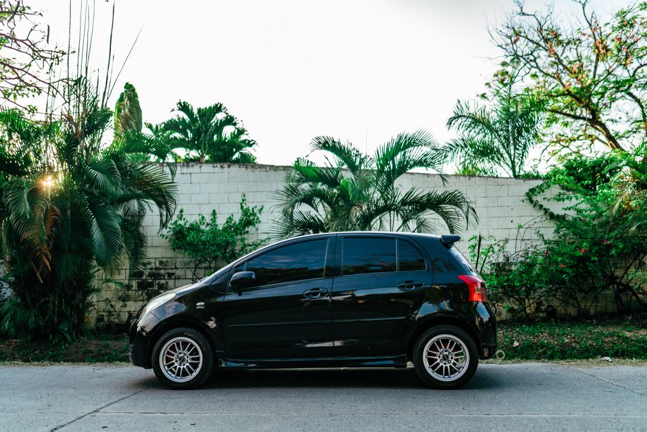 black Toyota Yaris compact car parked tropical beach road southern Thailand palm trees