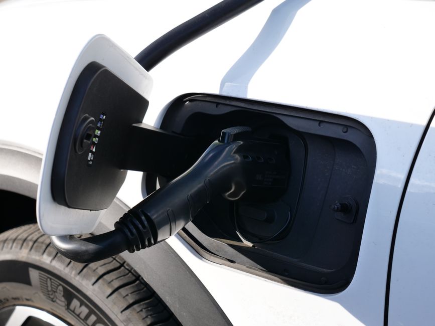 electric car plugged into a charging cable at an EV charging bay, close-up of charger connector