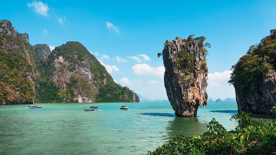 Limestone islands rising from calm turquoise sea Phang Nga Bay Thailand boat view
